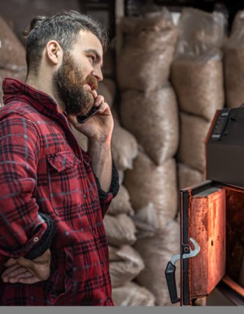 A man in a room with a solid fuel boiler, working on biofuel, economical heating.
